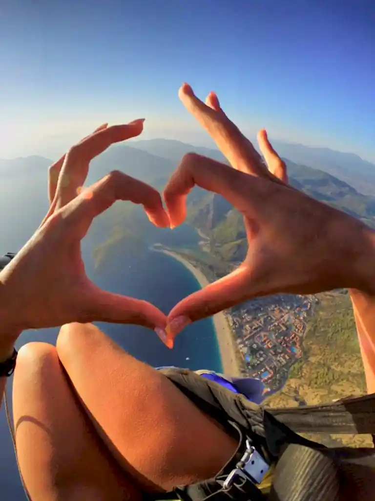 A paragliding passenger creating a heart shape above the stunning blue lagoon, capturing the romance and beauty of Oludeniz