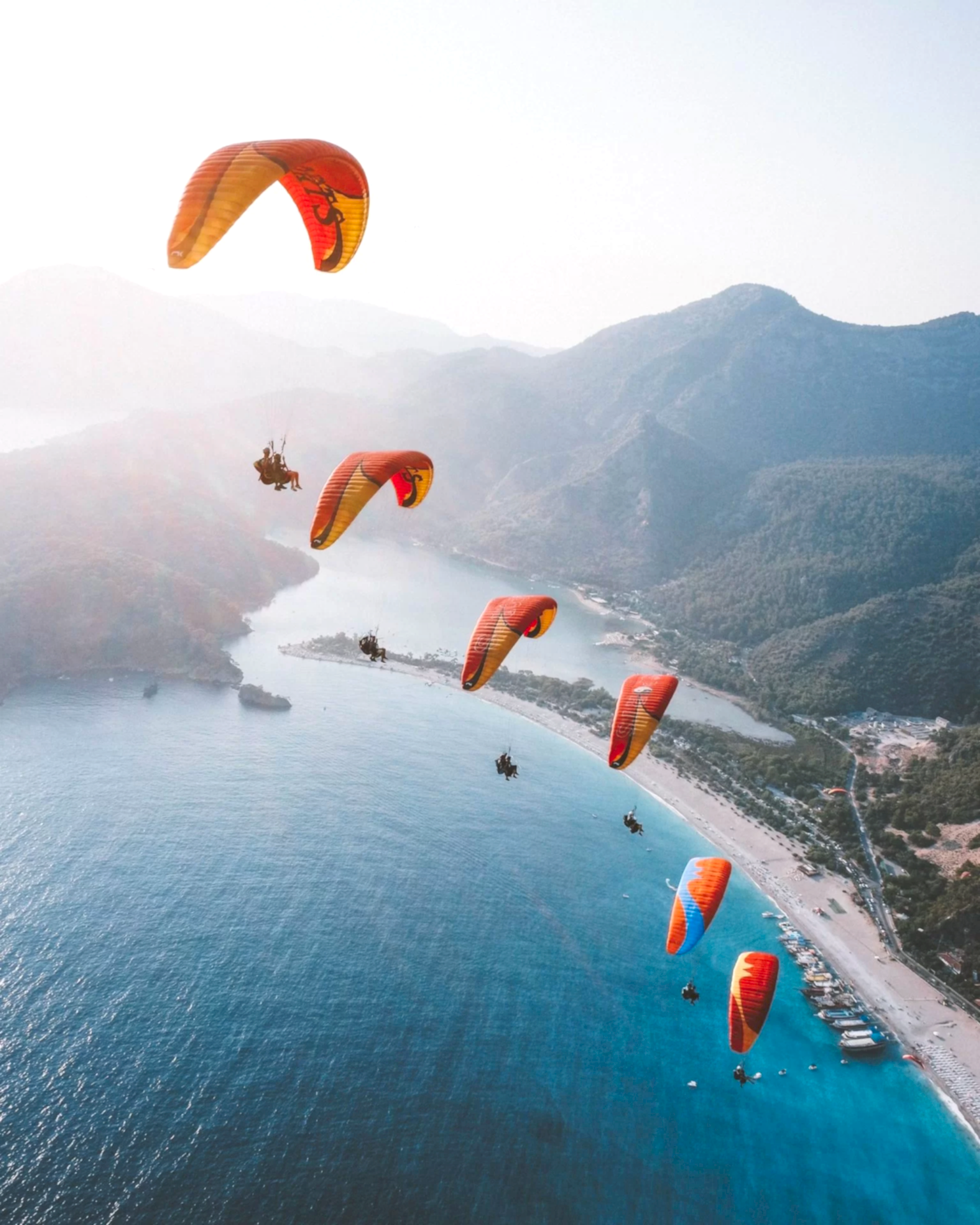 Six paragliders flying in perfect formation, side by side, showcasing precision and teamwork in the skies